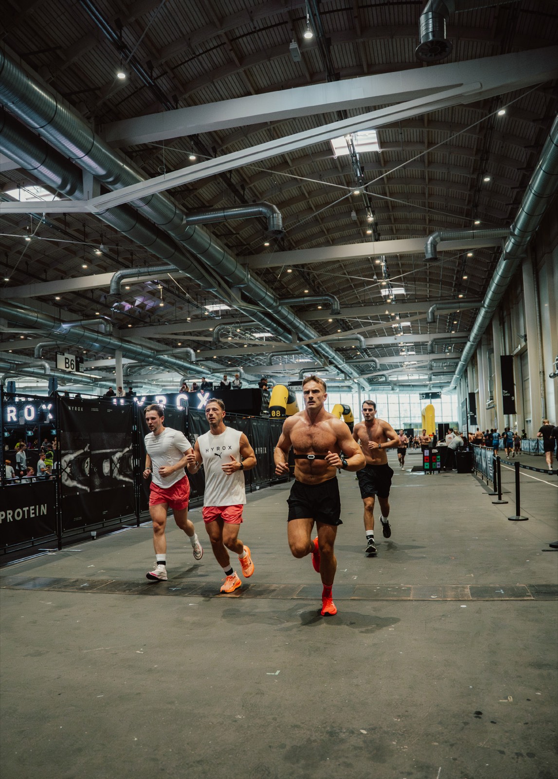 HYROX athletes running inside a competition arena